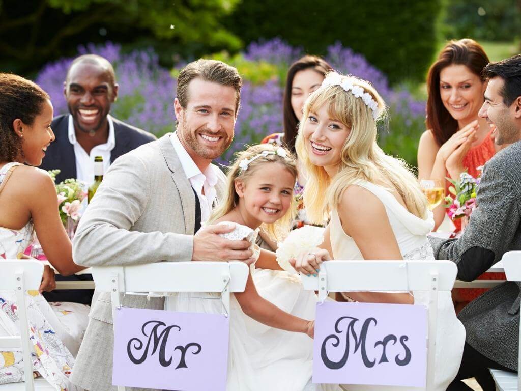 Hochzeitsfoto Idee mit Kindern: Brautpaar sitzt mit Kind am Brauttisch