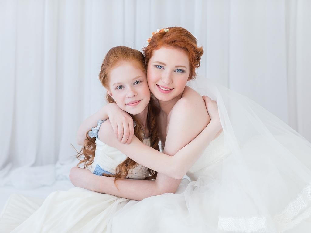 Hochzeitsbilder Ideen mit Kindern: Braut und Tochter nehmen sich sitzend in den Arm