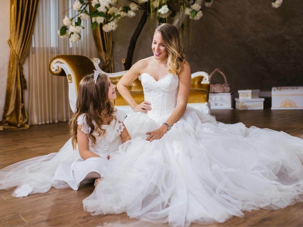 Hochzeitsfoto Idee mit Kindern: Braut sitzt mit kleiner Tochter auf dem Boden mit schön drapierten Kleidern