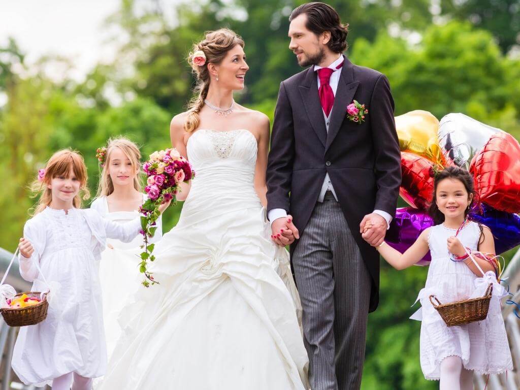 Hochzeitsfoto Idee mit Kindern: Brautpaar läuft gemeinsam mit den Kindern Hand in Hand einen Weg entlang