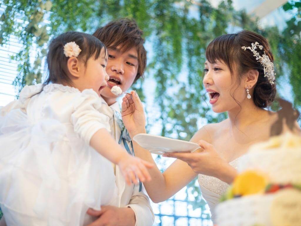 Lustige Hochzeitsfoto Idee mit Kind: Brautpaar füttert kleine Tochter mit Hochzeitstorte