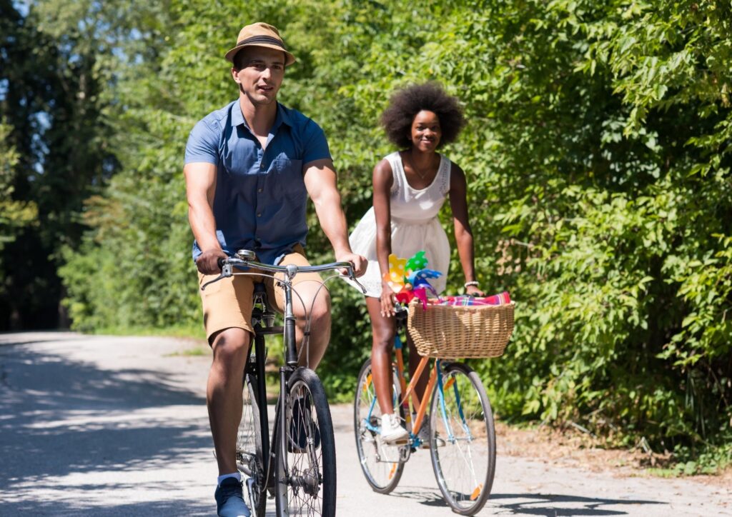 Verlobtes Paar fährt gemeinsam Fahrrad durch eine grüne Allee