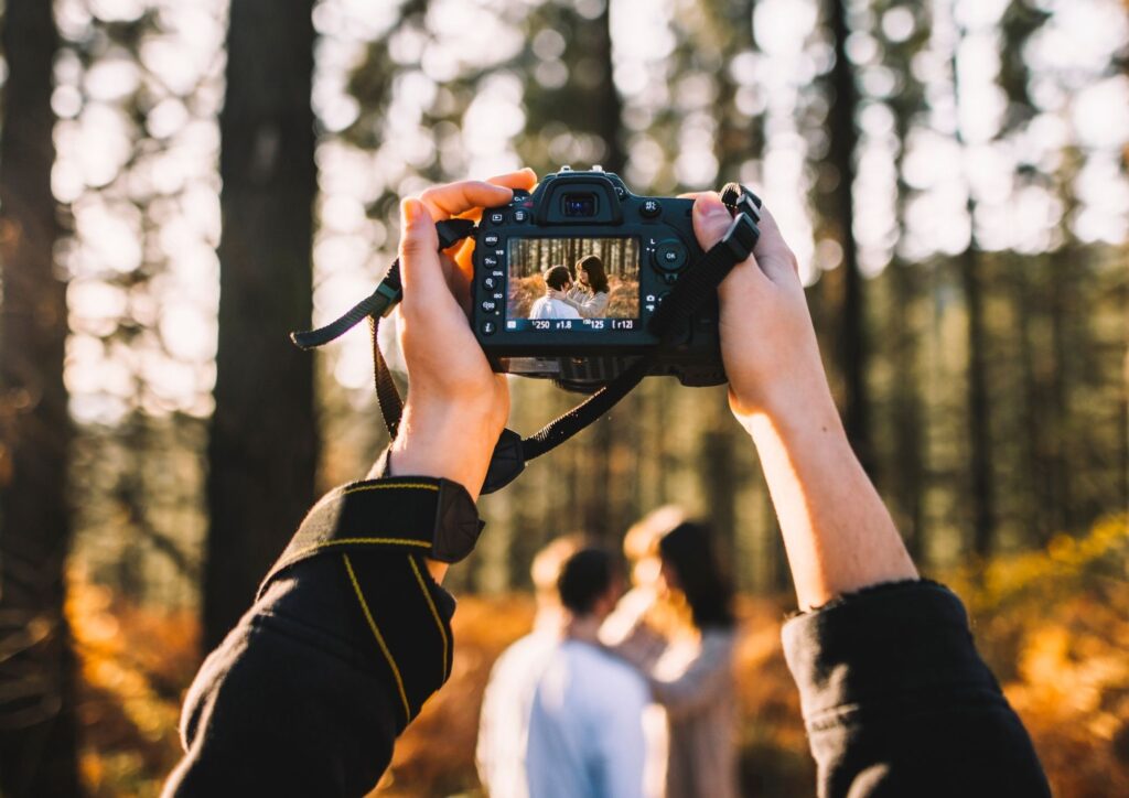 Fotograf hält ein verlobtes Paar bei einem Shooting im Wald fest