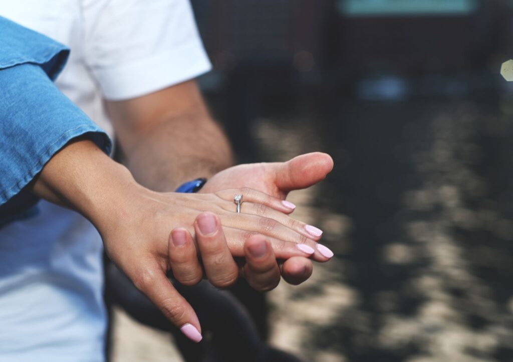 Paar hält Händchen und zeigt Verlobungsring