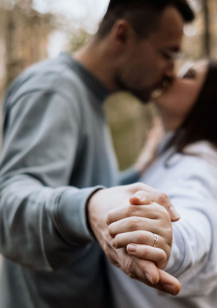 Paar küsst sich und zeigt den Verlobungsring