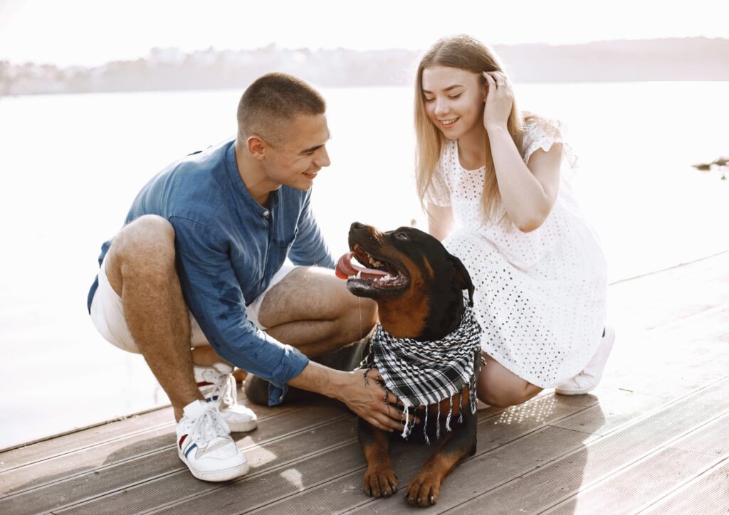 Verlobtes Paar sitzt mit seinem Hund am See