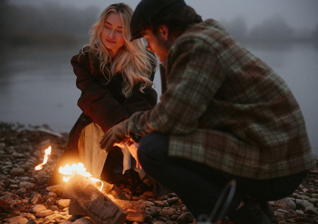 Paar sitzt an einem Lagerfeuer am See