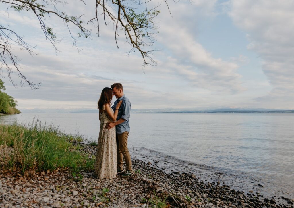 Verlobtes Paar steht eng umschlungen am Seeufer