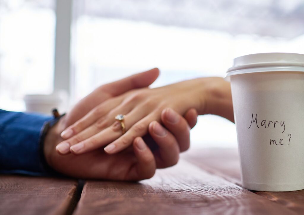  Zwei Hände neben einem Coffee-to-go-Becher
