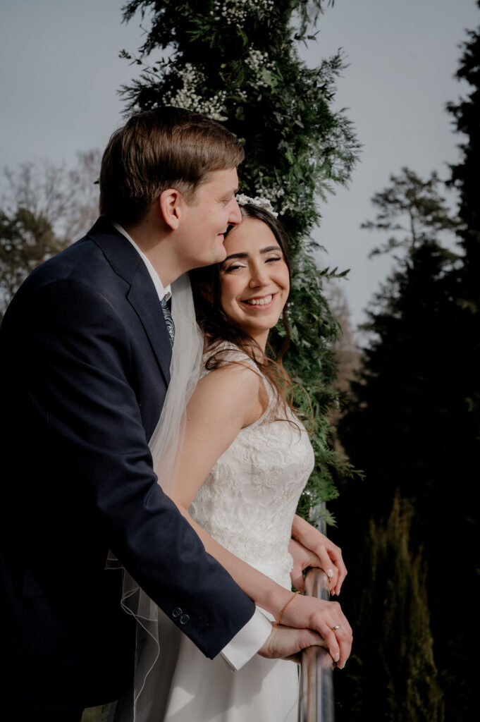 Bräutigam umarmt Braut von hinten – Löffelchen-Pose für Hochzeitsfotos