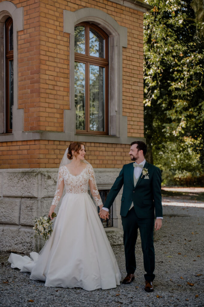 Brautpaar steht nebeneinander und schaut sich an – unkomplizierte Pose für Hochzeitsfotos