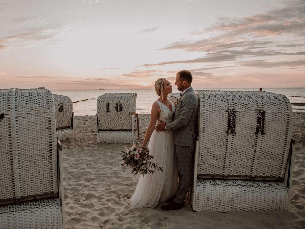 Hochzeit im Norden - Brautpaar posiert am Strandkorb an der Ostsee